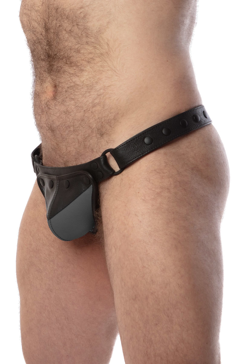 Model wearing a black leather thong with a grey shadow codpiece. Matt black hardware. Side view.
