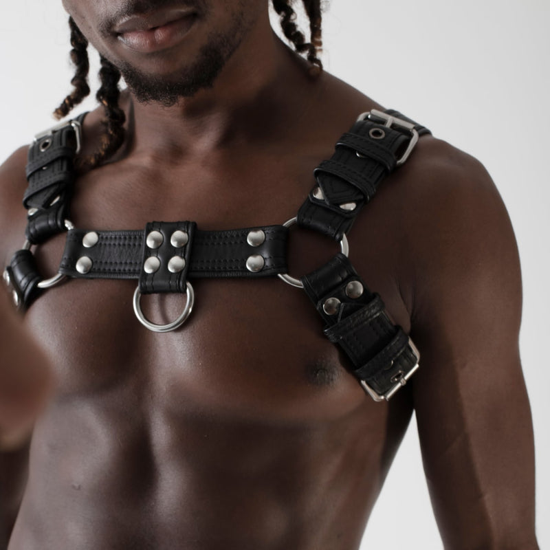Black leather chest harness with stainless steel hardware worn by male model