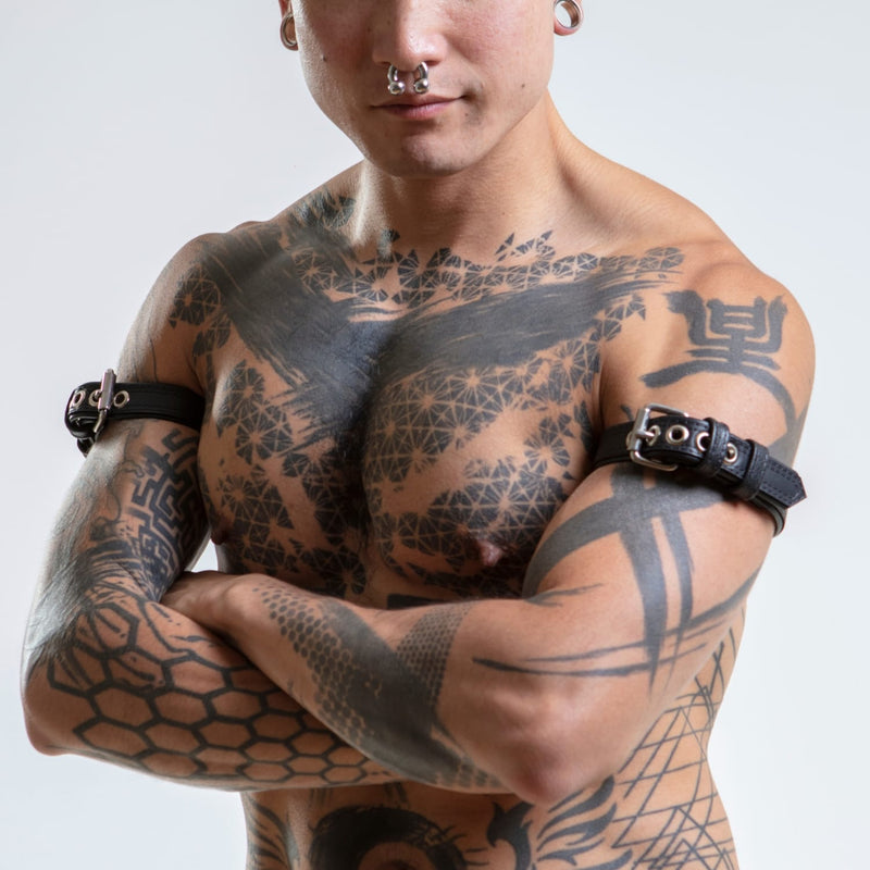 Tattooed male model wearing a matching pair of leather armband belts