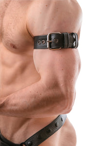 Tight-angled shot of a chiselled model in a black leather armband belt featuring stainless steel details.