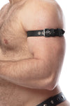 Close-up side view of a model wearing a 1" wide black leather buckled armband with stainless steel hardware.