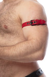 Side close-up of a hairy model showing a 1" wide red leather buckled armband with matte black hardware.
