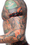 Tight profile shot of a model fitted in a 1" wide black and red leather buckled armband with matte black buckle.