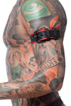 Close-up side view of a model wearing a 1.5" wide black and red leather armband with matte black hardware.