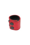 A red leather ball stretcher with matte black snaps, looped into a ring.
