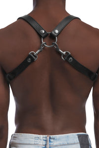 A fit model turned away wearing a 1" wide leather UNIVERSAL BRACES with stainless steel hardware, worn as a shoulder harness.