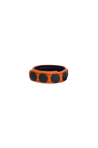 A curled orange leather cockring with matte black components.
