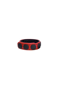 A 3/4" wide red leather cockring with matte black hardware, curled into a ring.