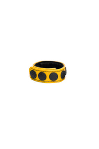 A yellow leather cockring with matte black snaps, looped into a ring.