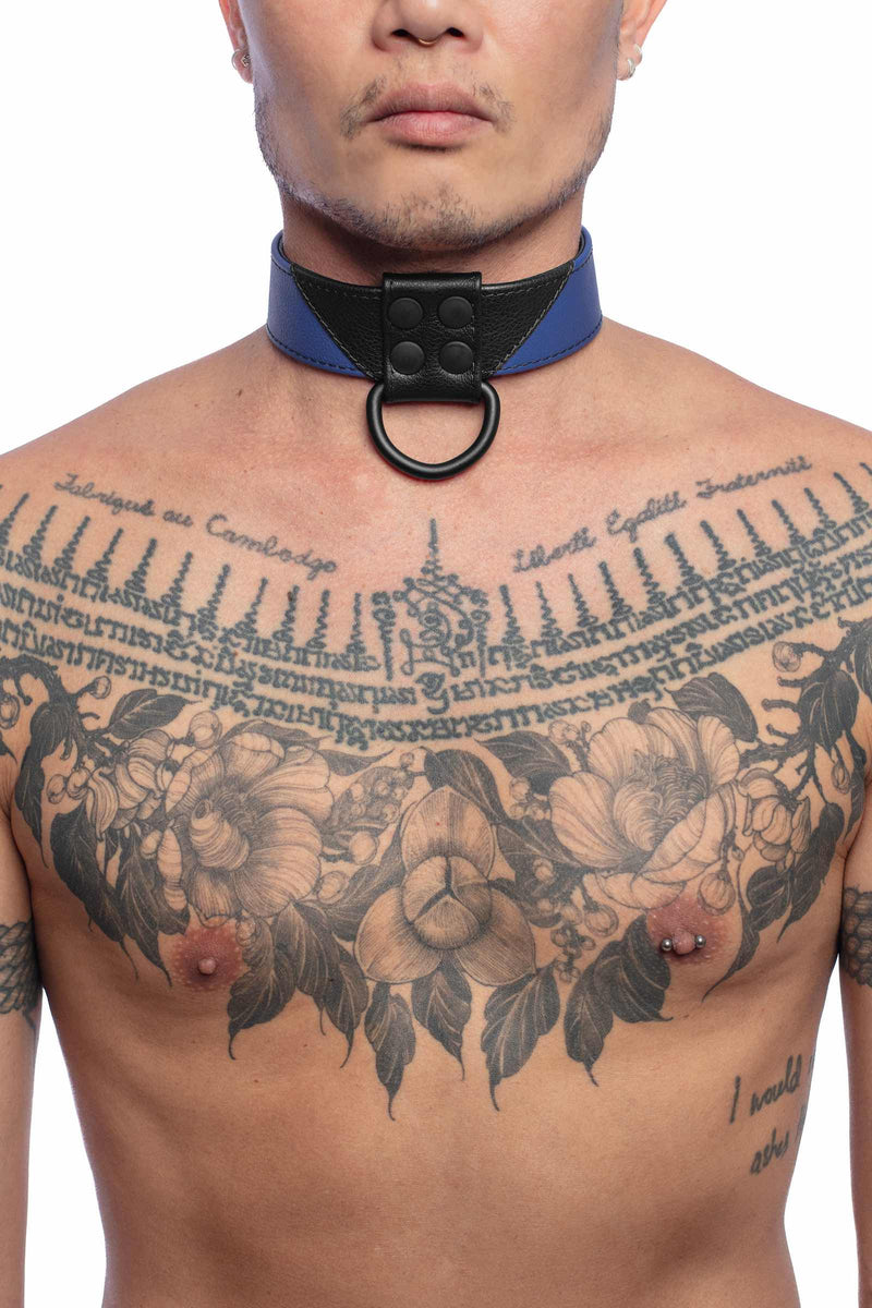 A 1.5" wide ARMY OF MEN CHEVRON COLLAR - Blue with black rivets and D-ring, worn by a tattooed male model.