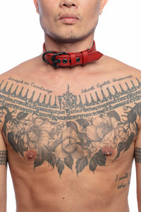 A tattooed model wearing a 1" wide CLASSIC COLLAR NARROW - Red with matte black rivets, buckle, and D-ring. 