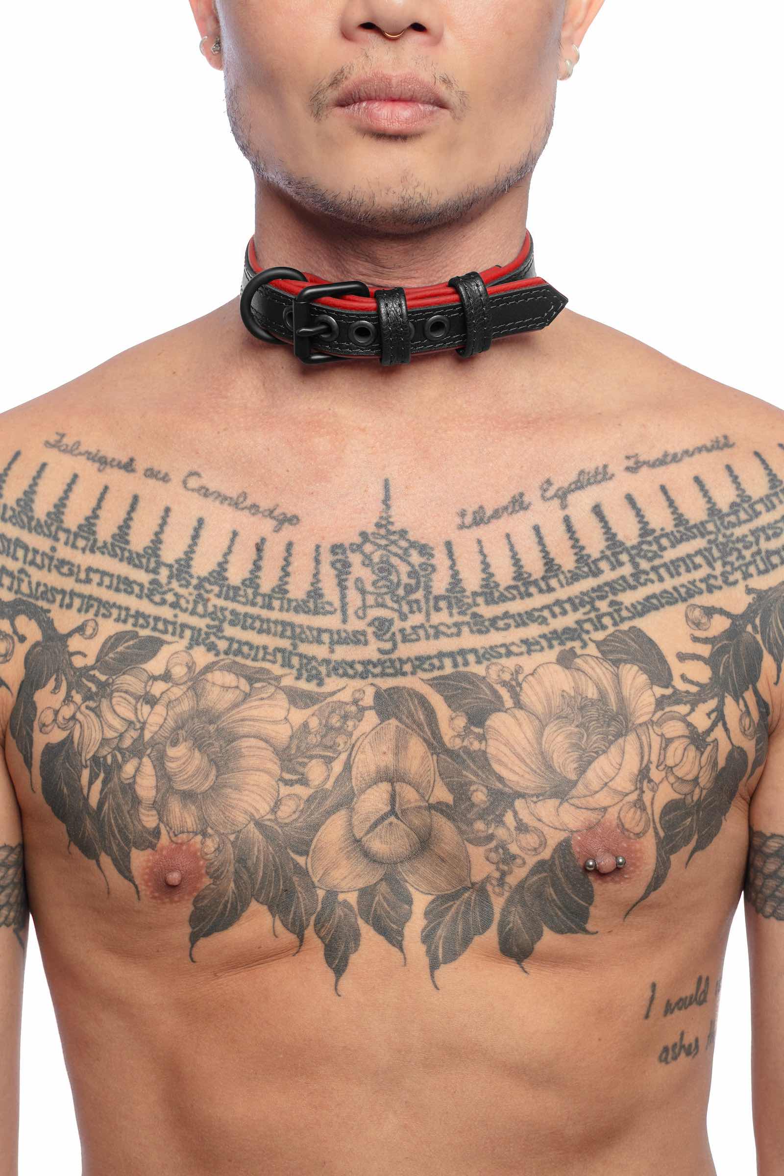 A striking model facing forward wearing a 1" wide ARMY OF MEN black and red leather collar with matte black hardware.