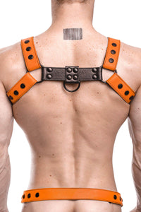 Rear view of chiselled model wearing a 1.5" wide ARMY OF MEN orange and black leather harness with matte black O-rings.