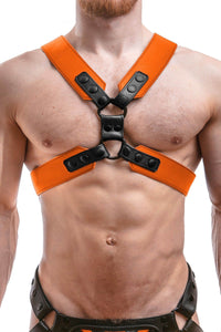 Male model in a 2" wide ARMY OF MEN COMMANDER X HARNESS - Orange with black rivets, snaps, and O-rings, front facing view.