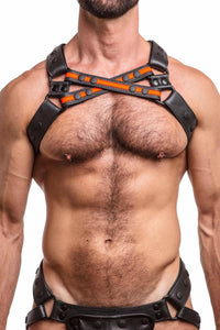 Male model in a black and fluro orange leather harness with black hardware, front facing view. Front straps crossed.