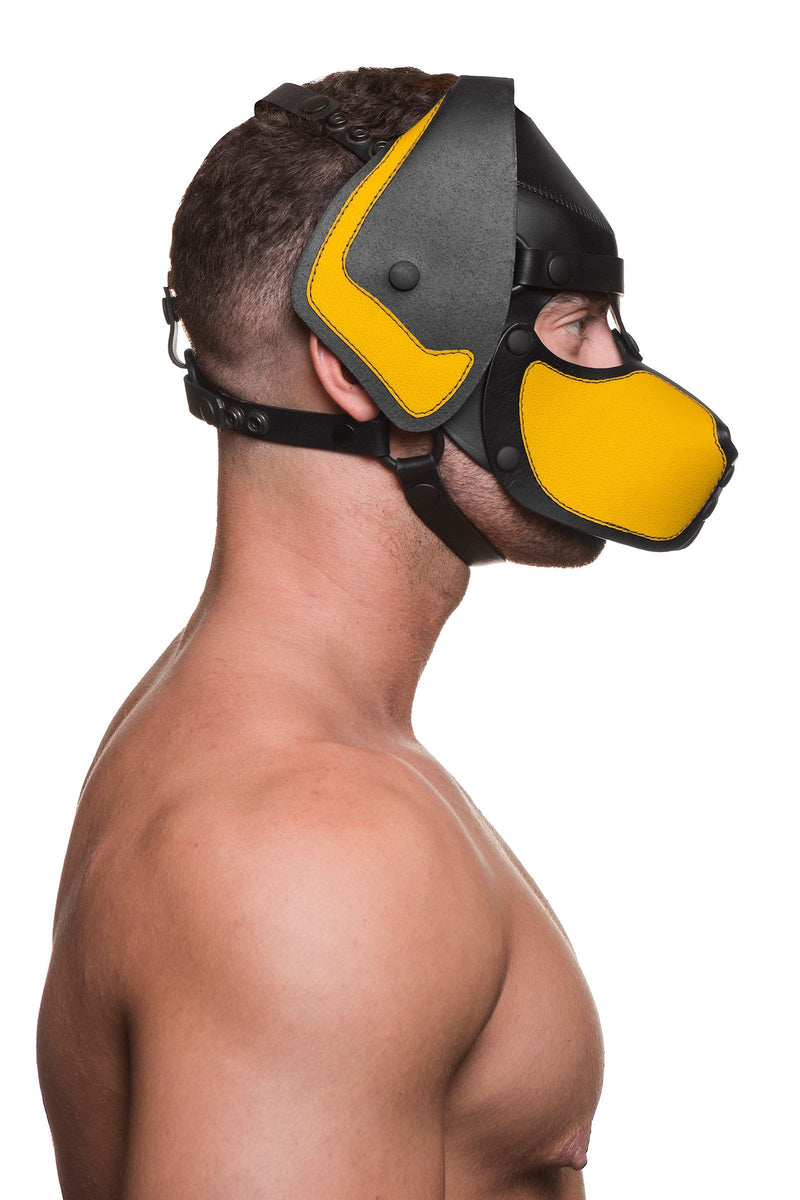 Pictured from the side, a bare-chested male model wears a handmade leather ARMY OF MEN pup hood, with yellow snout and ears.