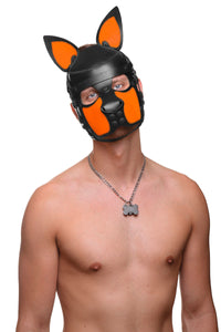 Cute toned model with his head quizzically tilted, is wearing a leather pup hood, with fluorescent orange ears and snout.