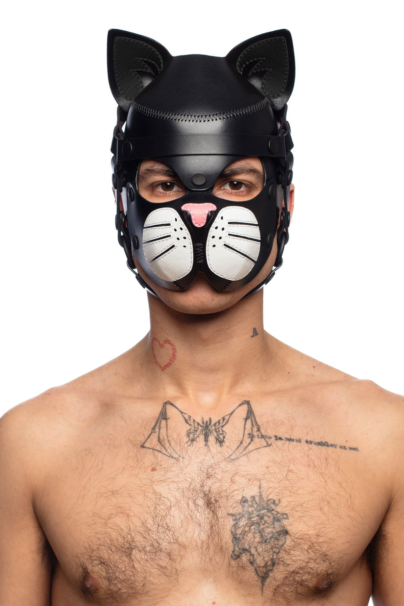 Portrait photo of a male model sporting a striking black leather TOMCAT hood, with white whisker pads, and a soft pink nose.