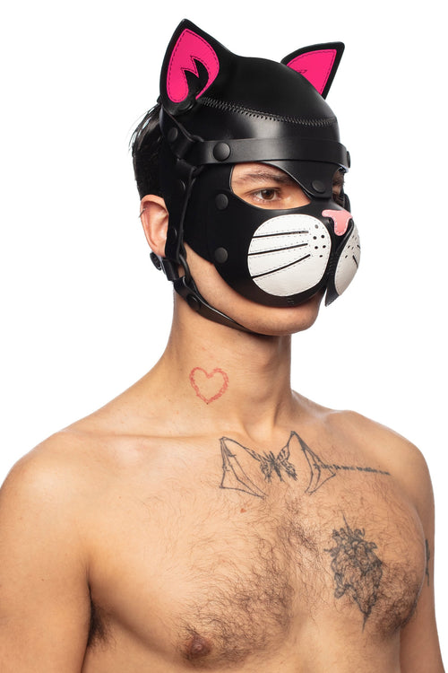 Framed chest-up at a subtle diagonal, the handsome male model is styled in a leather cat hood, with fluorescent pink ears.