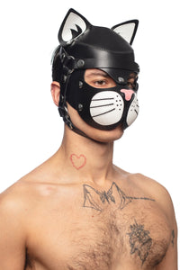 Model in a three-quarter pose from the chest up, in a black and white leather TOMCAT hood with stainless steel elements.
