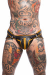 A tattooed model facing forward in an unique ARMY OF MEN COMBAT JOCK - Yellow with matte black rivets, snaps, and O-rings.