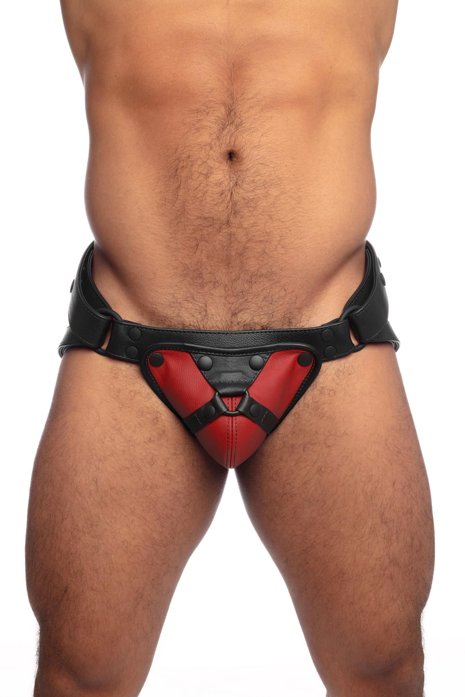 Front on view of a thick male model in a red and black leather jockstrap.