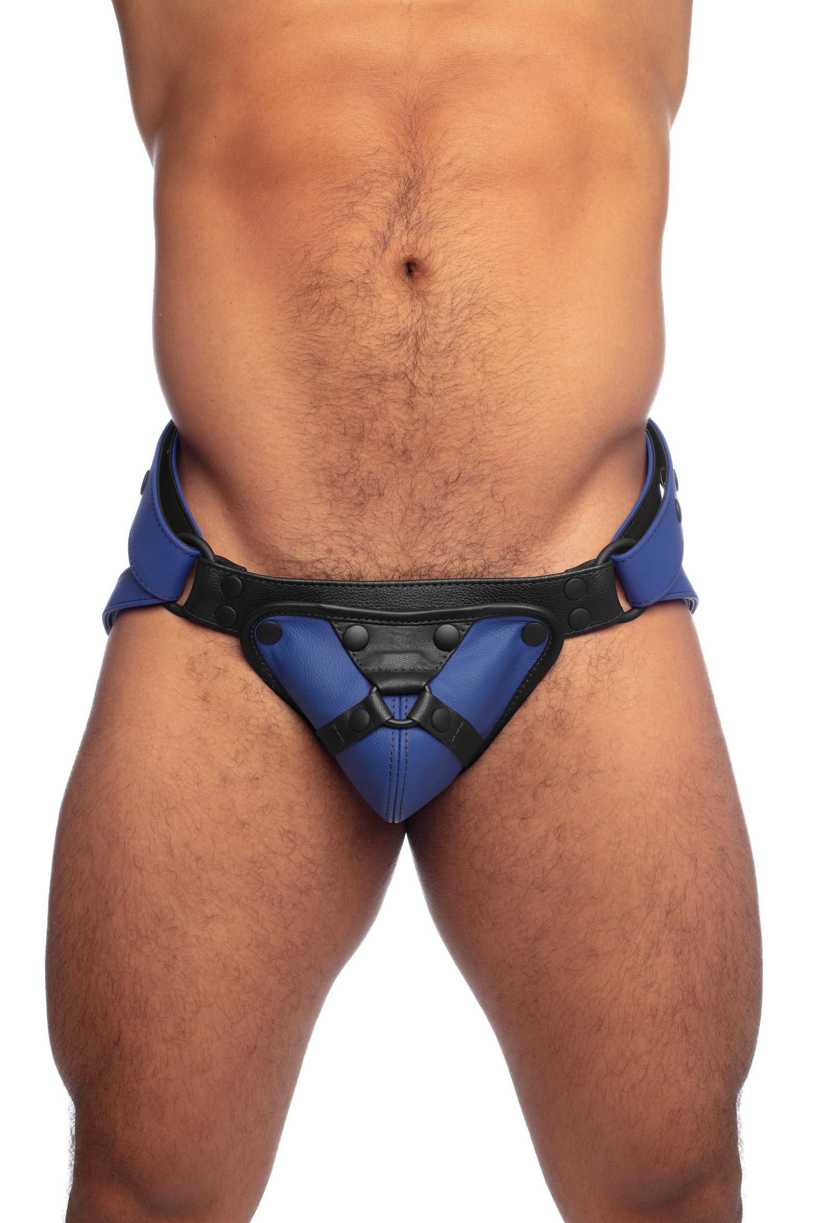 Front view of a muscular male model in a blue and black harness jockstrap.