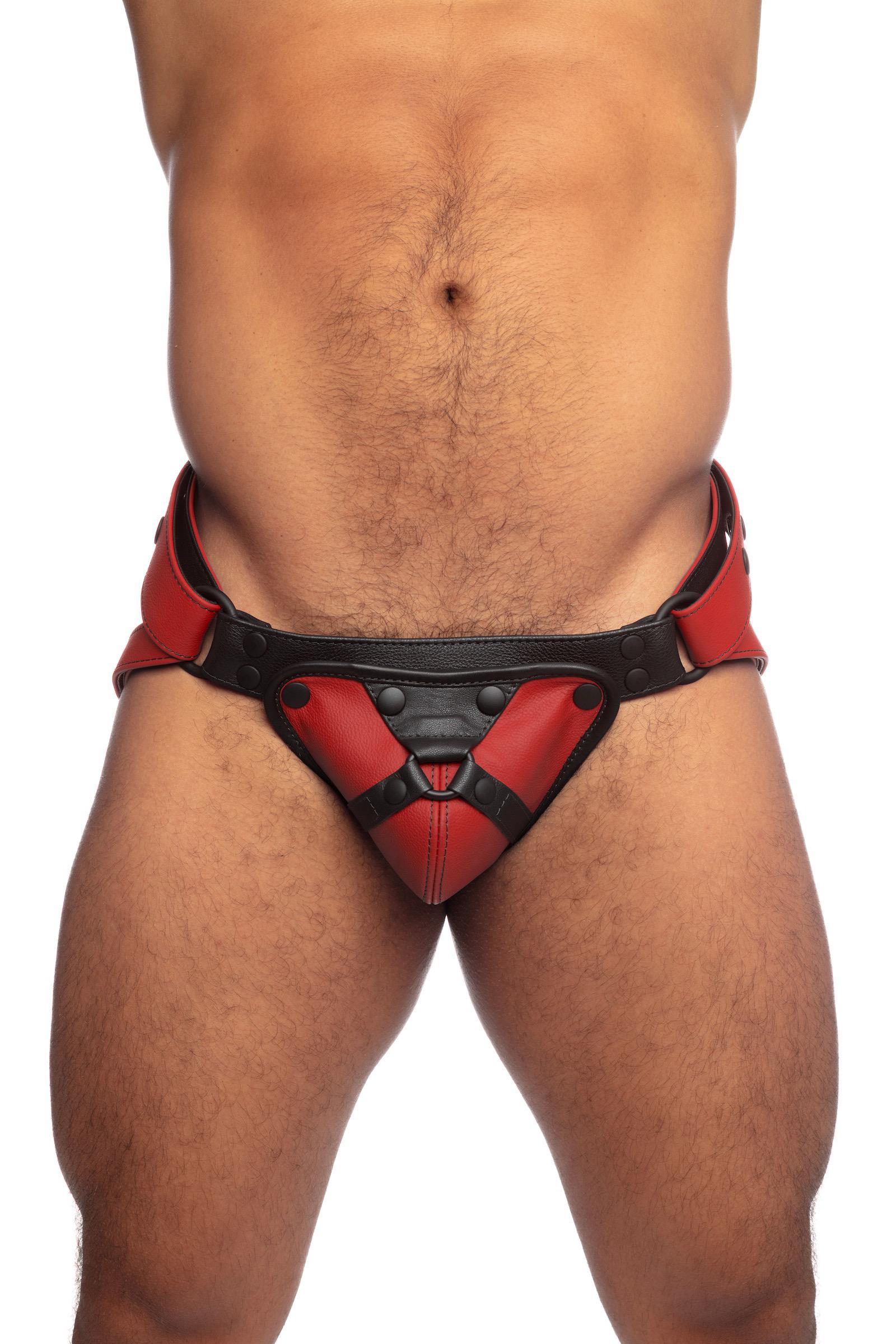 Front view of a model in a red and black leather jockstrap with detachable codpiece.