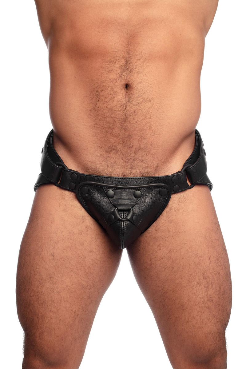 Muscular male model wearing a black leather harness jockstrap. Front view.