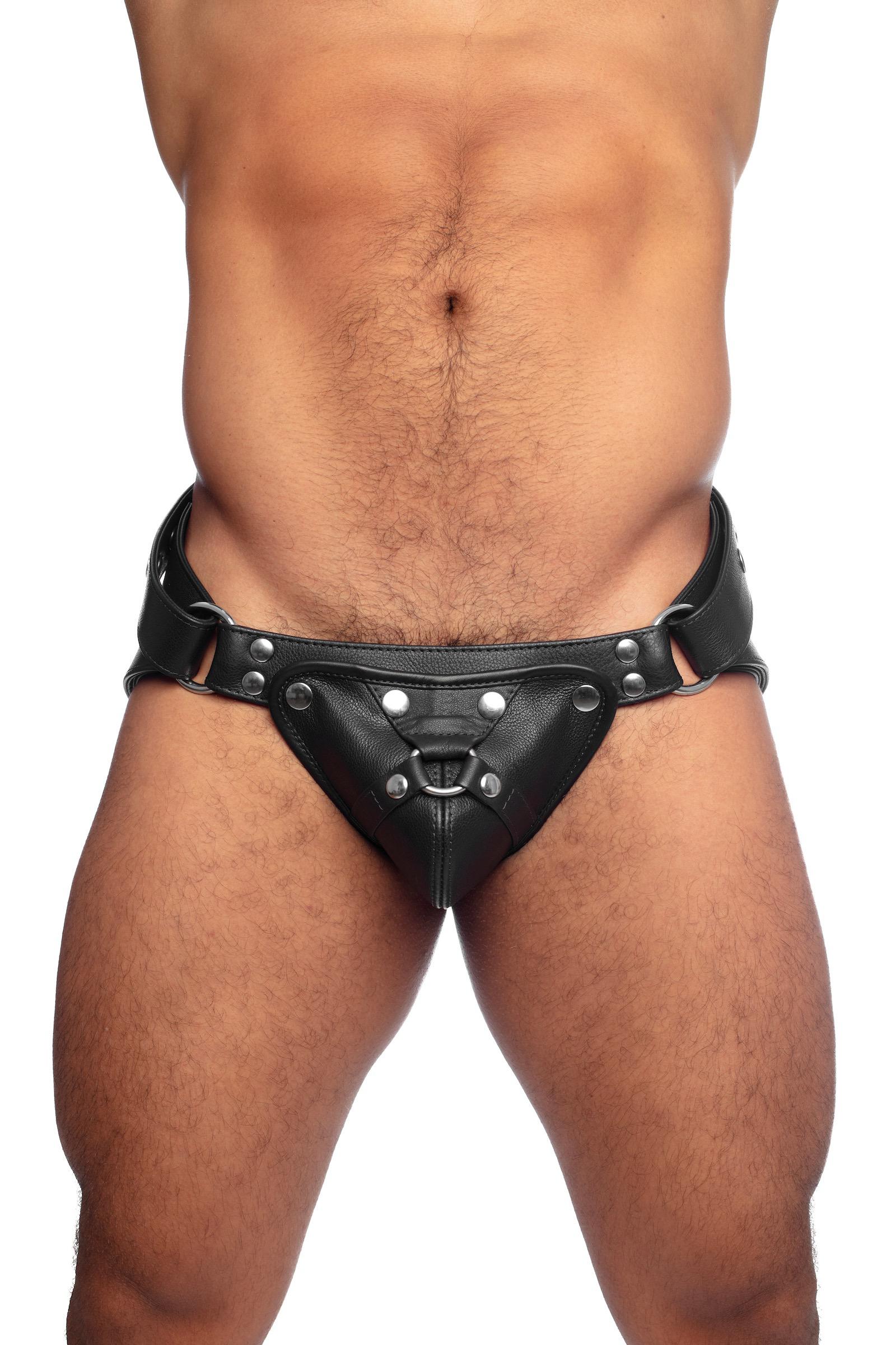 Model wearing a black leather harness jockstrap with stainless steel hardware. Front view.