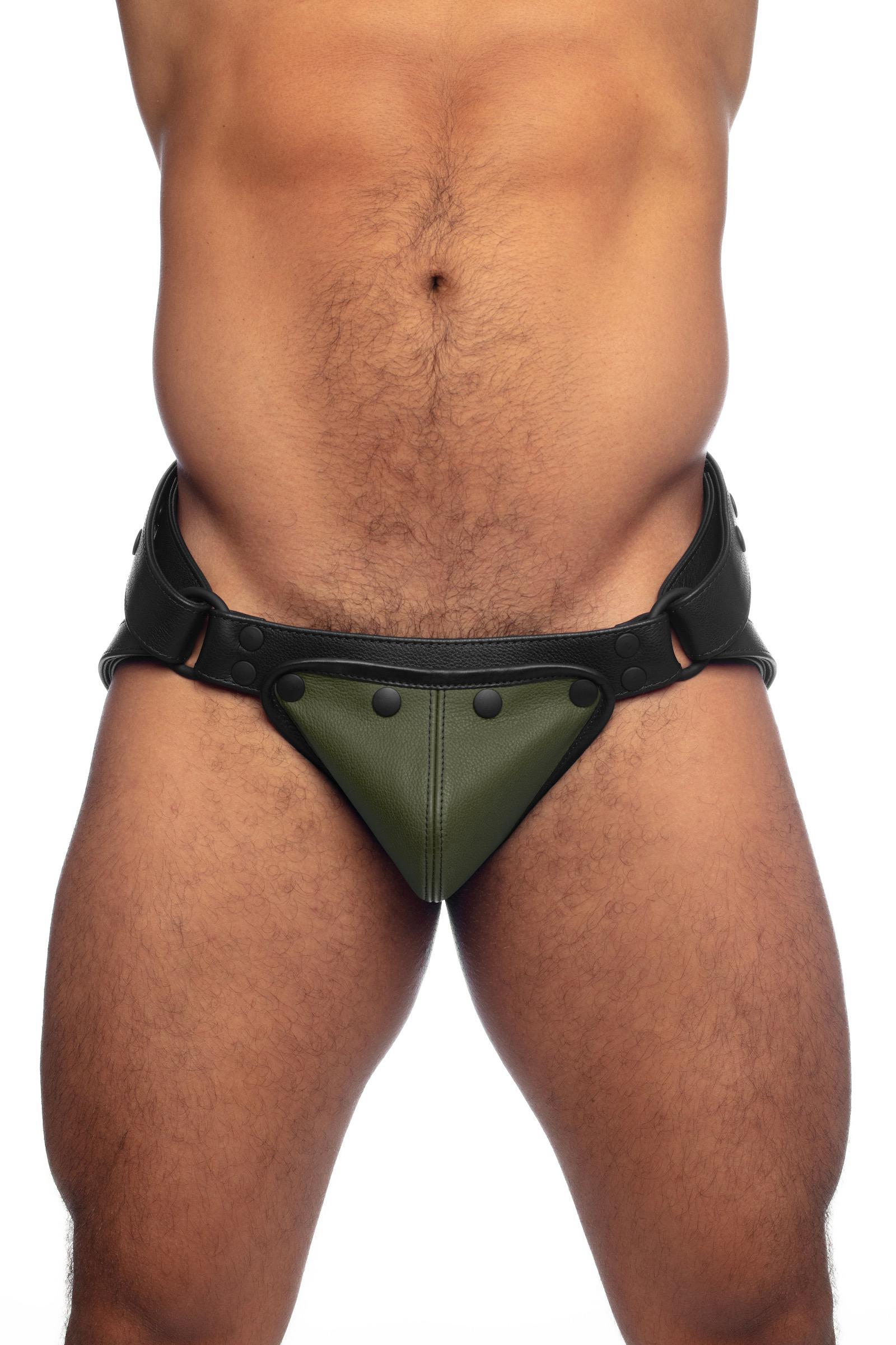 Muscular model in a black leather jock with army green codpiece. Front view.