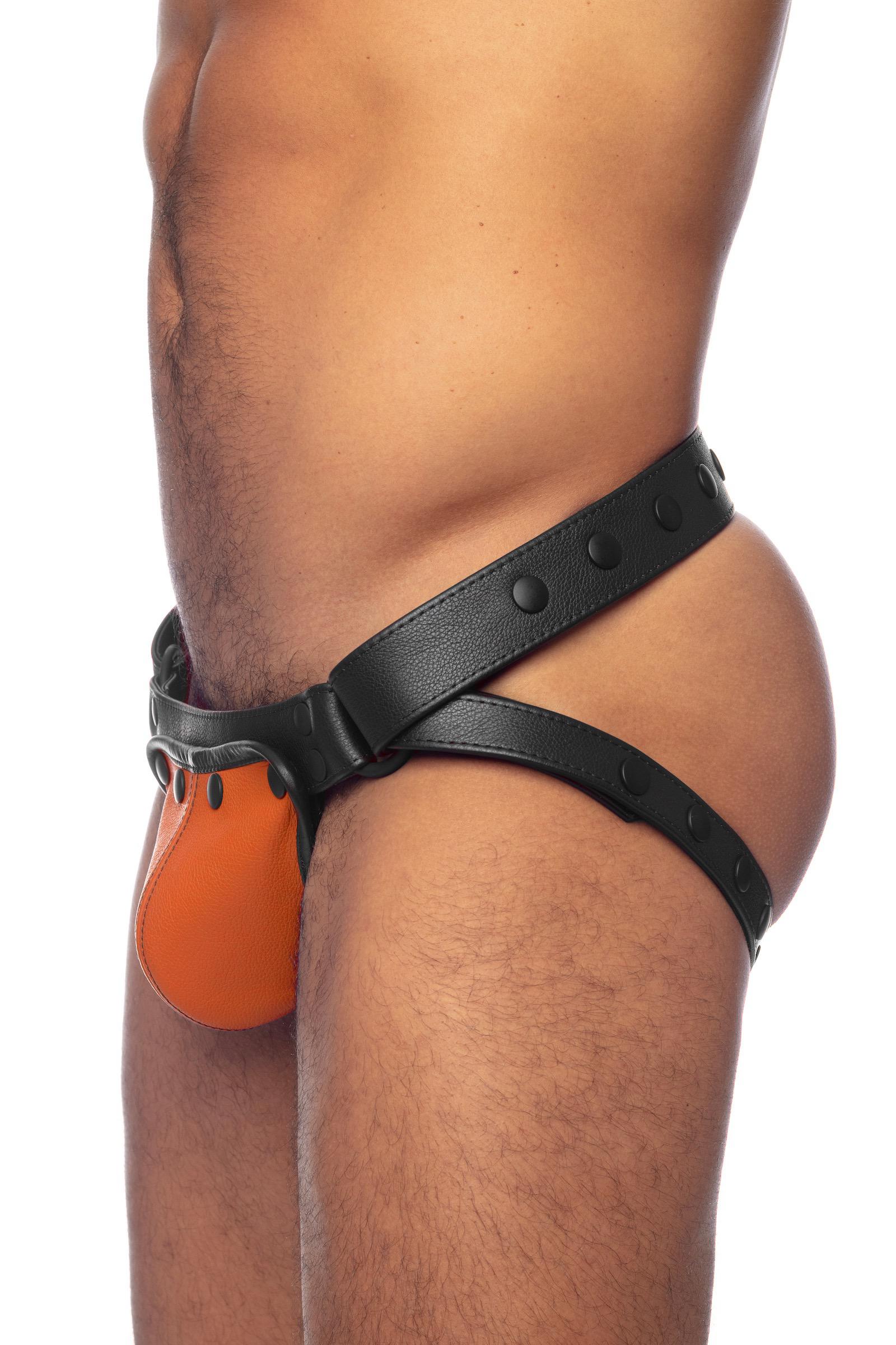 Thick male model wearing a black leather jockstrap with orange codpiece. Side view.