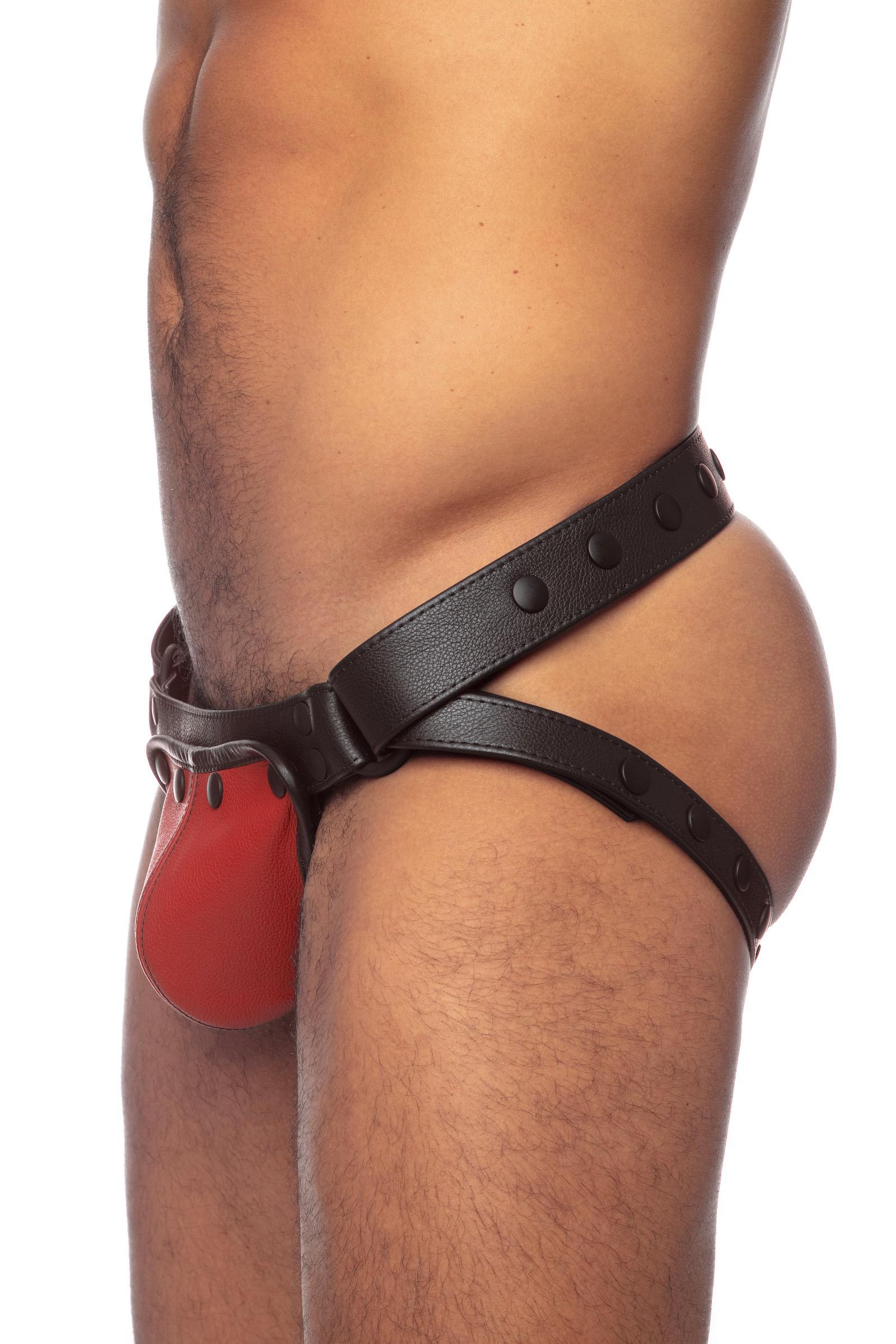 Side view of a male model wearing black leather jockstrap with a red leather codpiece.