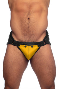Muscular male model in a black and yellow leather jockstrap. Viewed from the front.