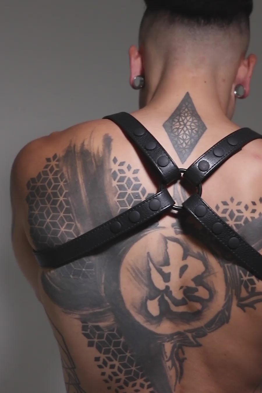 Model wearing black leather shoulder buckle harness with black hardware