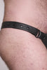 Video of a model wearing a black leather thong with a black harness codpiece. Matt black hardware
