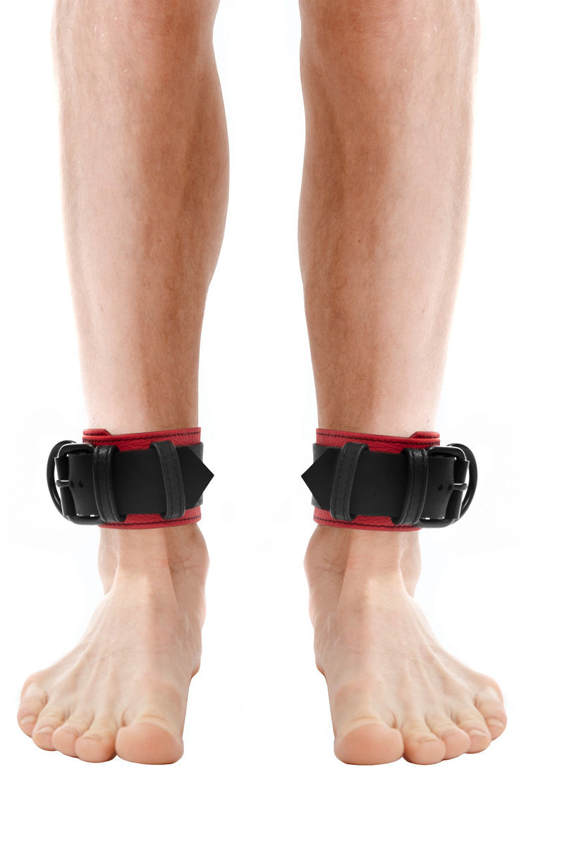 Fit model in a pair of 2.25" wide ARMY OF MEN ANKLE RESTRAINTS - Red with matte black buckles and D-rings, front facing view.