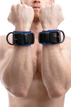 Front view of model wearing a pair of 2.25" wide ARMY OF MEN black and blue leather restraints with matte black hardware.
