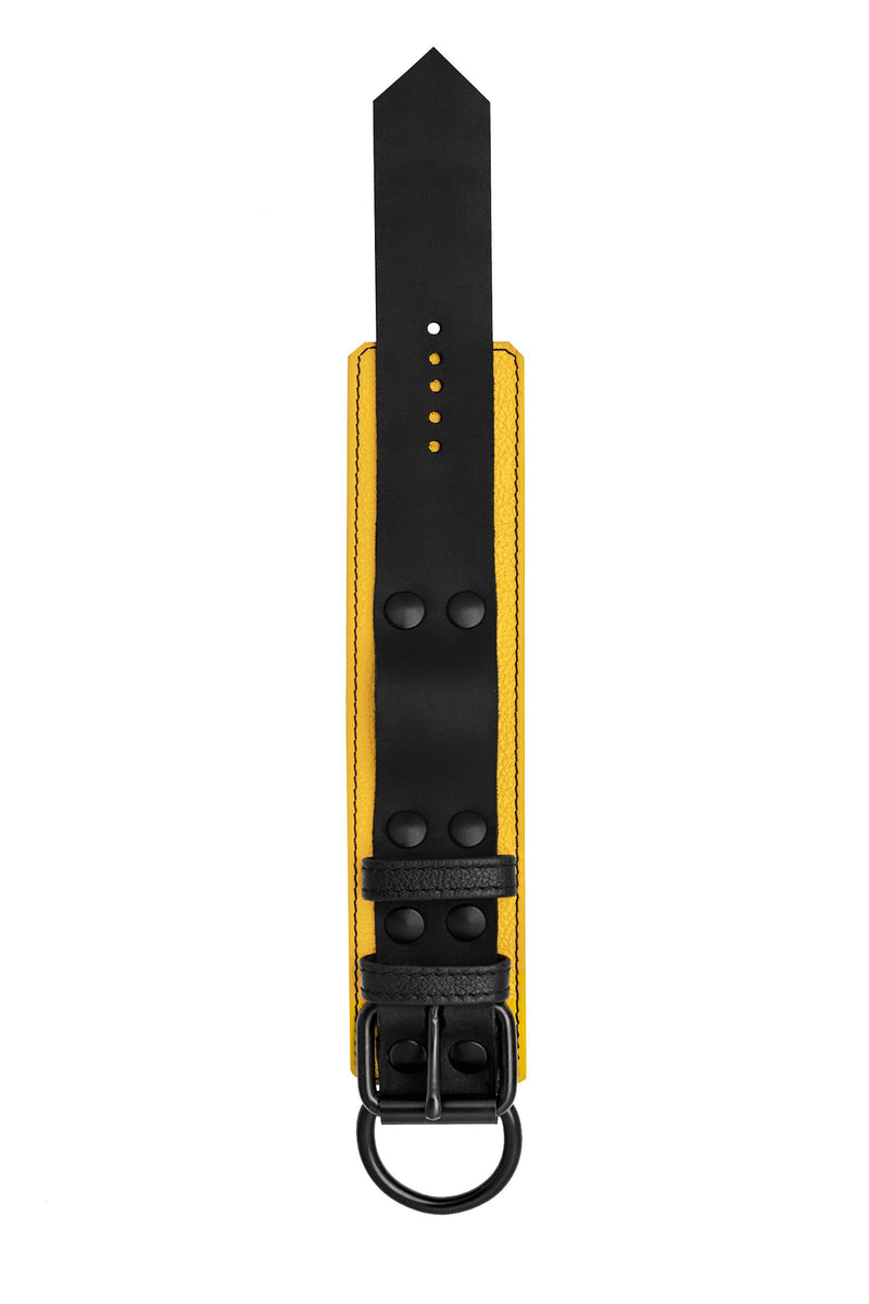 A 2.25" wide ARMY OF MEN black and yellow leather wrist restraint with matt black hardware, laid flat and viewed from above.