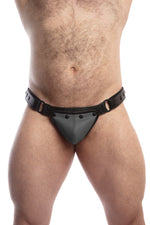 Model wearing a black leather thong with a grey codpiece. Matt black hardware. Front view.