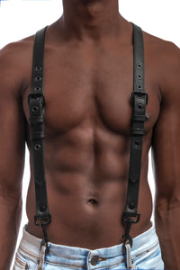 Model wearing black leather braces with black metal hardware attached to jeans. Front 1.