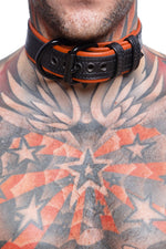Model wearing a 1.5" black and orange leather pup collar. Close up view.