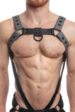 Model wearing a grey leather bulldog harness and connector with black hardware. Connector attached to a cockring. Front.