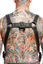 Model wearing a black and army green leather combat harness and connector with black metal hardware. Back view.