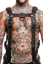 Model wearing a black and army green leather combat harness and connector with black metal hardware. Front view.