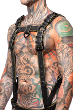 Model wearing a black and army green leather combat harness and connector with black metal hardware. Side view.