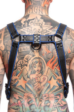 Model wearing a black and blue leather combat harness and connector with black metal hardware. Back view.
