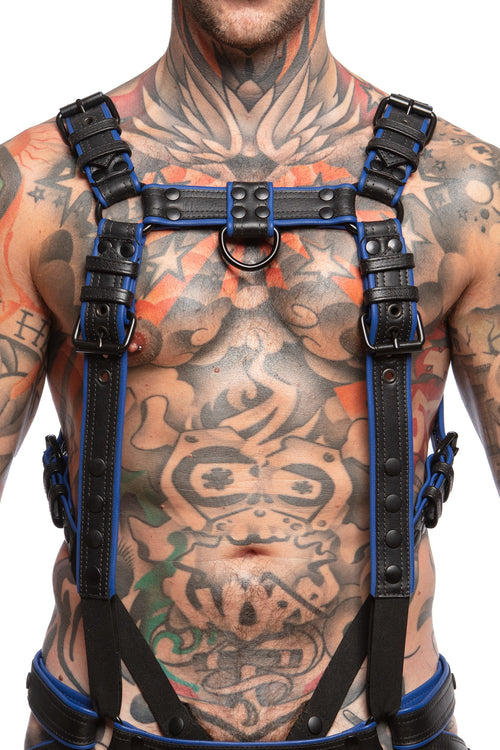 Model wearing a black and blue leather combat harness and connector with black metal hardware. Front view.