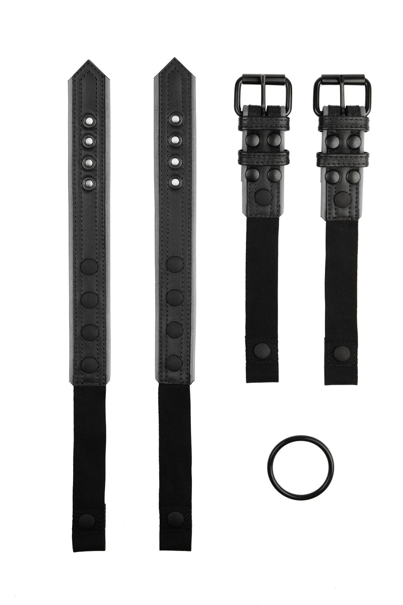 Pair of black and grey leather combat harness connectors with black hardware. Separated. Front view.