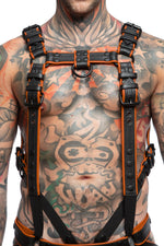 Model wearing a black and orange leather combat harness and connector with black metal hardware. Front view.
